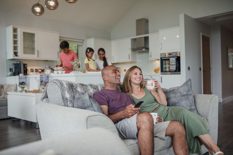 How to make your new house feel like home. Family relaxing on couch and kitchen after recently moving into house.