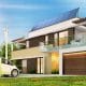 Sustainable and energy efficient home improvements. House with solor panel on roof, elctic car charging station and windmills