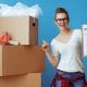 Moving house checklist. Woman standing infront of packing boxes while holding a checklist.